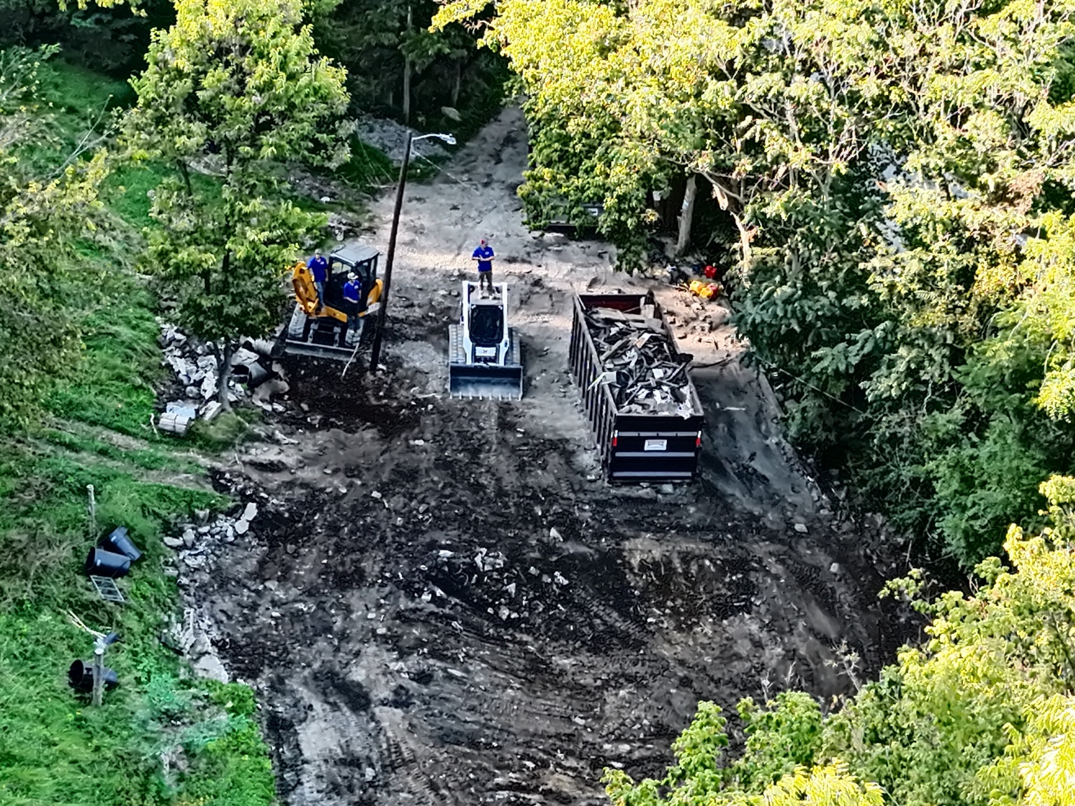 Aerial view of a Starrett Junk Removal demolition cleanup with skid steer, excavator, and dumpster